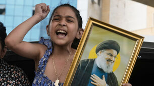 <p>A displaced child holds a picture of Hezbollah leader Naim Qassem (Bilal Hussein/AP)</p>
