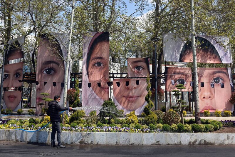 At Tajrish Square in Tehran, a gardener waters plants in front of portraits of children killed in the  missile strike on a school in the city of Minab which killed at least 165 people, most of them children. Picture: AFP/Getty