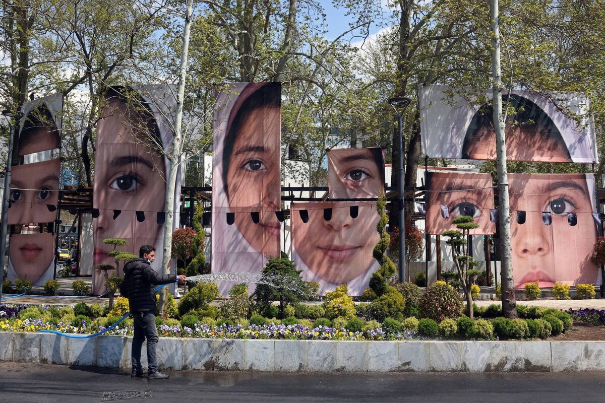 A gardener waters the plants in front of the portraits of children killed in a deadly strike on a children's school in the southern city of Minab on the first day of the war that killed at least 165 people, most of them children, at the Tajrish Square in Tehran on April 16, 2026.  (Photo by AFP via Getty Images) / 