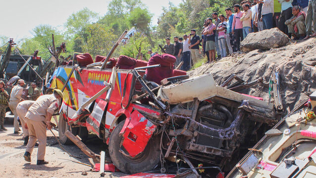 Policemen inspect the wreckage of a passenger bus after it rolled down from a hill (AP)