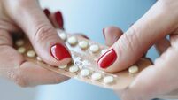 Woman with red manicure holding blister with contraceptive hormonal pills in her hands closeup