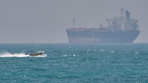 <p>A boat sails past a tanker anchored on the Strait of Hormuz off the coast of Qeshm island, Iran (Asghar Besharati/AP)</p>