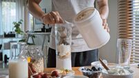 Young adult Asian man prepare and make protein shake drink, mixed fruit cereal juice, using blender mixer. Fitness dietary activ