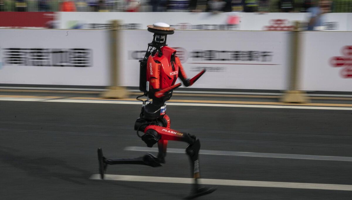 The fastest humanoid robot, an H1 made by Honor, runs beside human runners at the start on its way to winning the Beijing Humanoid Half Marathon in Beijing. Pic: Kevin Frayer/Getty Images.