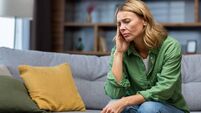 Mature woman alone at home with boss and depressed, housewife sitting upset on sofa holding head with hands in living room