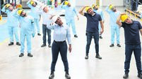 Employees doing stretching exercises during their break at a warehouse