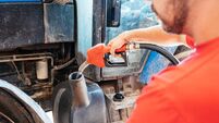 Close-up of Young Farmer Refueling a Tractor With a Gas Pump in the Countryside During Daytime