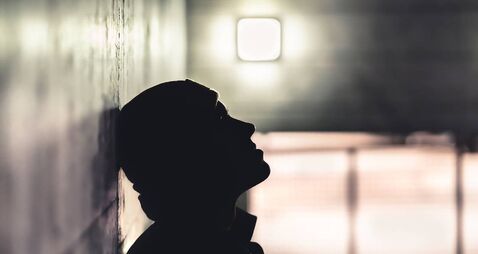 Serious sad man in dark. Depressed anxious person suffer from trauma, solitude or drug addiction. Homeless outcast with shame af