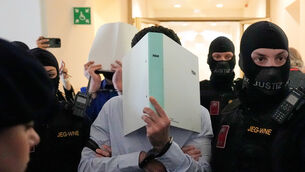 The defendants hide their faces behind file folders on their way to the courtroom (Matthias Schrader/AP)