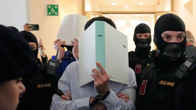 The defendants hide their faces behind file folders on their way to the courtroom (Matthias Schrader/AP)
