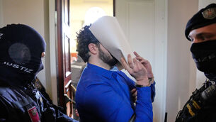 A defendant hides his face on the way to court (Matthias Schrader/AP)