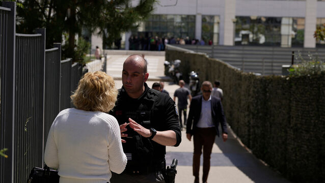 A policeman speaks to a woman outside a court building (Petros Giannakouris/AP)