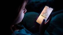 A child using smart phone lying in bed late at night
