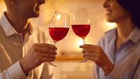 Man and woman in love enjoying red wine and clinking glasses on romantic evening at home