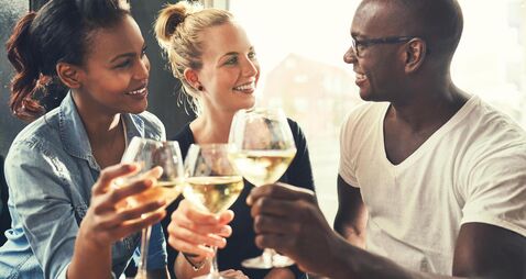 Ethnic friends at a bar drinking wine and eating tapas