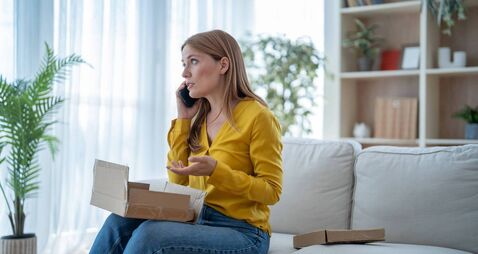 Woman complaining on phone about damaged package at home