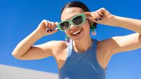 Cheerful woman in sunglasses beaming brightly under cloudless azure sky
