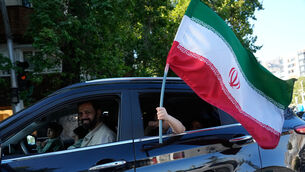 <p>A child holds an Iranian flag through the window of a vehicle in northern Tehran (Vahid Salemi/AP)</p>
