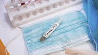 Test tube labeled Hantavirus on a mask, with gloves in a lab setting