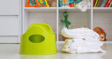 Green potty and toilet paper in the room.