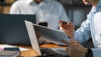 Businessman analyzing documents and working on laptop in office meeting