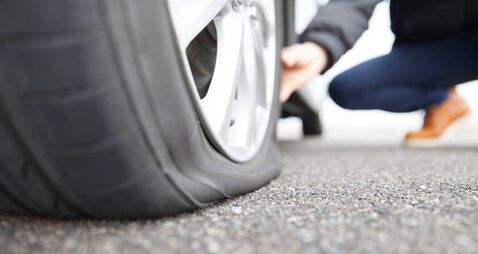 man touching a flat tire on the roadside