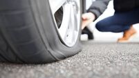 man touching a flat tire on the roadside