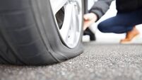 man touching a flat tire on the roadside
