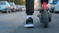 Close-up of a man riding an electric scooter on a street. Ground view