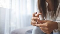 Unhappy woman holding wedding ring close up