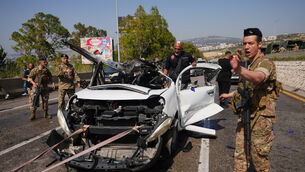 A Lebanese soldier gestures as security forces and emergency responders inspect a destroyed vehicle at the scene of an Israeli airstrike in the coastal town of Saadiyat, south of Beirut on Saturday (Hassan Ammar/AP)