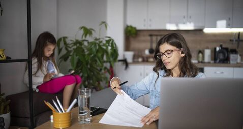 Busy bisness mother woking at home while little daughter being occupied by digital tablet