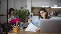 Busy bisness mother woking at home while little daughter being occupied by digital tablet