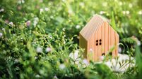 Living in a Harmony Lifestyle Concept. Wooden House Model on Green Grass. Close to Nature