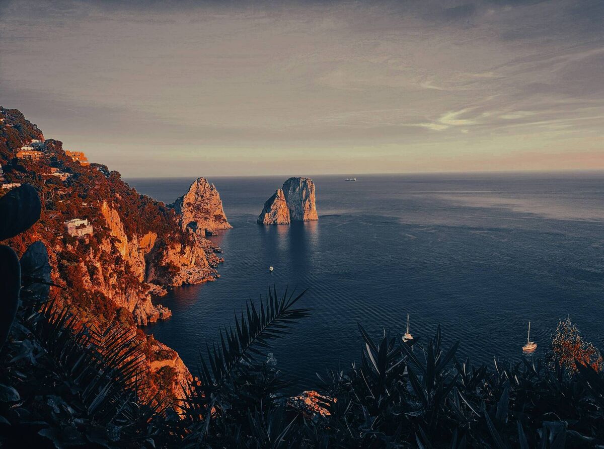 Capri at sundown, when the coastline softens into evening light and yachts drift quietly across the bay. Capri at sundown, when the coastline softens into evening light and yachts drift quietly across the bay.