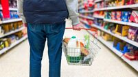 Man holding shopping basket with bread and milk groceries in supermarket
