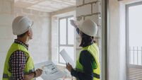 two engineers, a man and a woman in white helmets and green protective vests