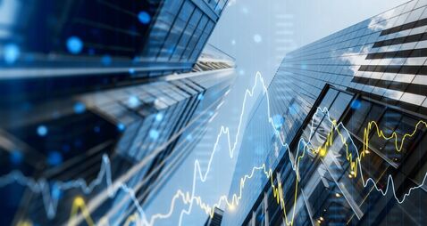 A double exposure image of skyscrapers with overlay of financial graphs, set against a blurred background, illustrating the conc