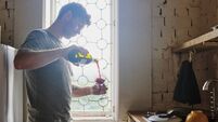 Pouring, kitchen and man with wine, home and alcohol to relax on weekend, window and guy in apartment. Lens flare, break and per