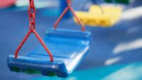 close up of empty children swing on children playground in the outdoor park in the soft-focus background