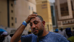 A Muslim pilgrim splashes water over his head to cool down outside the Grand Mosque (Altaf Qadri/AP)