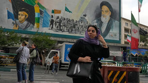 A woman crosses a street in front of a painting of the late Iranian revolutionary founder Ayatollah Khomeini and paramilitary Basij forces in downtown Tehran, Iran (Vahid Salemi/AP) A woman crosses a street in front of a painting of the late Iranian revolutionary founder Ayatollah Khomeini and paramilitary Basij forces in downtown Tehran, Iran (Vahid Salemi/AP)