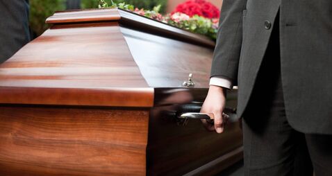 Funeral with casket carried by coffin bearer