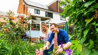 Contented mid adult couple gardening with sustainable solar panel house in background