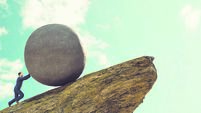 Concept of hard work for businessman pushing rock up a hill