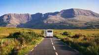 Landscape Scenery With White Bus Driving On Empty Scenic Road  With Mountains  At  Mayo, Ireland