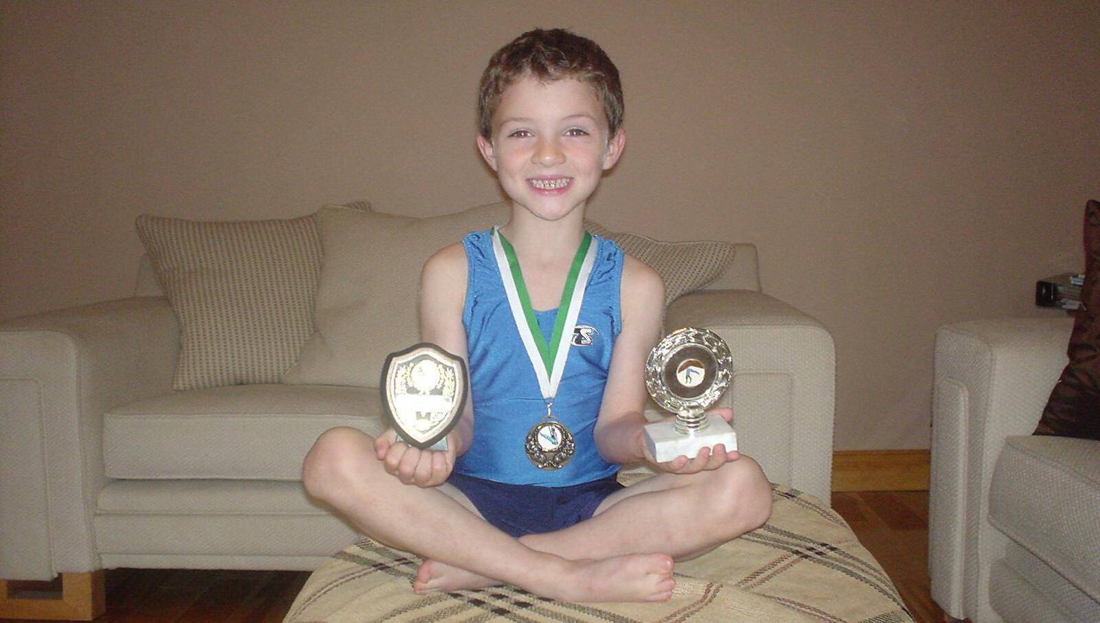 Rhys with trophies and medals from an underage gymnastics competition.
