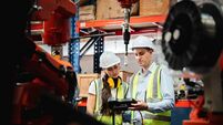 Industrial engineers control the automatic arms machine welding robotics in industrial manufacturing factories.