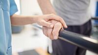 Female nurse touching senior man's hand on railing