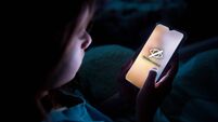 A child using smart phone lying in bed late at night